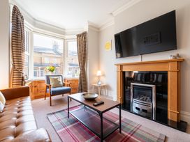 A living room with a sofa, armchair, and television at 18 Mayville Avenue, Scarborough