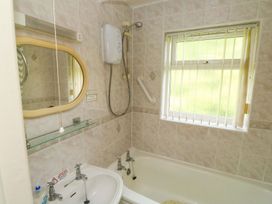 A bathroom with a bathtub, sink, and mirror at Cottage 28 in Brixham
