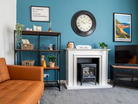 A living room with a sofa, bookshelf, clock, and fireplace at 53A Hampton Road Scarborough
