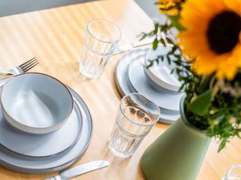 A dining table set with cutlery, plates, bowls, glasses, and a flower vase at 53A Hampton Road, Scarborough