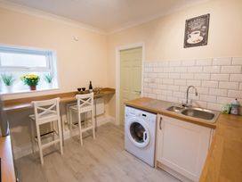 A kitchen with a washing machine and bar stools at 53 Hampton Road in Scarborough