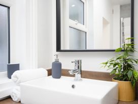 A bathroom sink with a mirror, soap dispenser, towels, and a plant at 46 Ashville Avenue, Scarborough