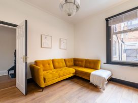A living room with a yellow sofa and door at 22 Ashville Avenue in Scarborough