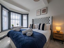 A bedroom with a bed, bedside table, lamp, and window at 22 Ashville Avenue Scarborough