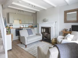 A living room with a fireplace and kitchen area at Primrose Cottage in Salcombe