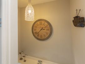 A bathroom with a wooden clock and pendant light at Primrose Cottage in Salcombe