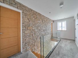 A hallway with a stone wall and glass railing at The Old Barn in Abergele