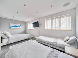A bedroom with three beds and a TV mounted on the wall at The Old Barn in Abergele