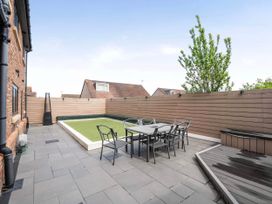 An outdoor patio with seating and a small lawn at The Old Barn in Abergele