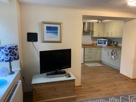 A living room with a television and kitchen area at 1 bed cottage Parking Patio close to coasts Coads Green near Launceston