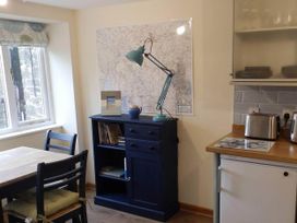 A kitchen with a table and bookshelf at 1 bed cottage Parking Patio close to coasts Coads Green near Launceston