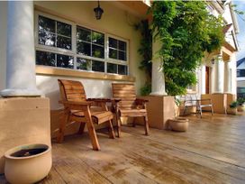 A outdoor seating area with wooden chairs and potted plants at Build your memories hot tub garden sleeps 14 Nottage