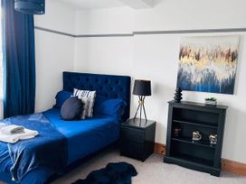 A bedroom with a blue bed and a shelf unit at Build your memories hot tub garden sleeps 14 Nottage