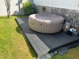 A hot tub with a plastic cover on decking in the garden at Build your memories hot tub garden sleeps 14 Nottage