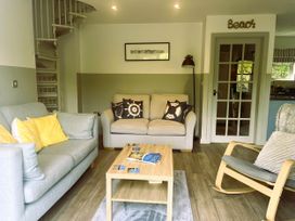 A living room with a sofa, armchair, coffee table, and spiral staircase at 2 Bedrooms overlooking Little Petherick Creek in Little Petherick