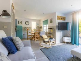 A living room with a television and dining table at 2 Bedrooms overlooking Little Petherick Creek in Little Petherick