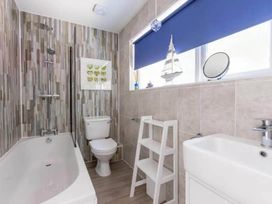 A bathroom featuring a bathtub, toilet, sink, and storage shelf at 2 Bedrooms overlooking Little Petherick Creek in Little Petherick