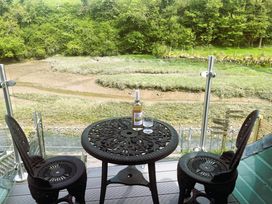 An outdoor table and chairs with a wine bottle and glass overlooking Little Petherick Creek in Little Petherick