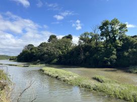 A riverbank with trees and grass at 2 Bedrooms overlooking Little Petherick Creek in Little Petherick