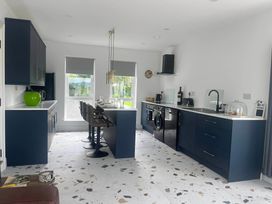 A kitchen with a sink and bar stools at Sunset Cottage  Sleeps 6 with Parking Garden in Magilligan near Limavady