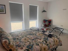 A bedroom with a bed and chair at Sunset Cottage Sleeps 6 with Parking Garden in Magilligan near Limavady