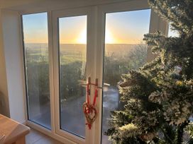 A view of a sunset through glass doors and a Christmas tree at Stunning 3 Bedroom Cottage near Historic York in Ampleforth