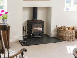 A living room with a wood stove and a basket of firewood at Stunning 3 Bedroom Cottage near Historic York in Ampleforth