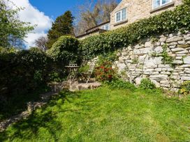 A garden with a table and chair near a stone wall at Stunning 3 Bedroom Cottage near Historic York in Ampleforth