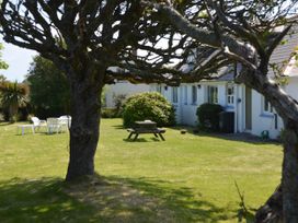 A garden with a tree, table, and chairs at House Sleeps 8 Close to Beach Free parking, Mullion