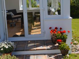 An outdoor entryway with flowers and a view into a seating area at House Sleeps 8 Close to Beach Free parking, Mullion