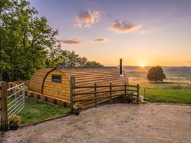 A wooden structure with a chimney at sunset at The Lodge at Brambles Farm Sleeps 4 Hot Tub in Leek