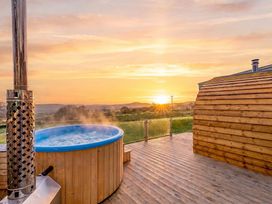 A hot tub on a wooden deck during sunset at The Lodge at Brambles Farm Sleeps 4 Hot Tub Leek