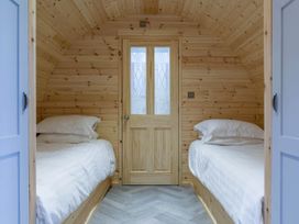 A bedroom with two beds and a wooden door at The Lodge at Brambles Farm Sleeps 4 Hot Tub in Leek