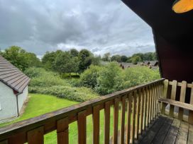 A balcony view of trees and grass at Cosy 3 Bedroom House on Cornish estate with pool St Tudy