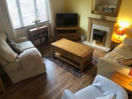 A living room with a television, coffee table, and armchairs at Cosy 3 Bedroom House on Cornish estate with pool St Tudy