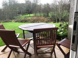 An outdoor patio area with a table and chairs at Cosy 3 Bedroom House on Cornish estate with pool, St Tudy