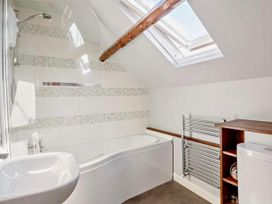 A bathroom with a bathtub, shower, wash basin, towel rail, and toilet at Cottage Sleeps 5 with Parking and Garden, Carreglefn