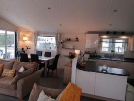 A living room with a dining area and kitchen units at Seaside Lodge Retreat in Eyemouth