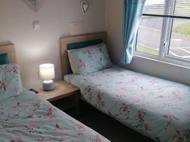 A bedroom with two beds and a lamp at Seaside Lodge Retreat in Eyemouth