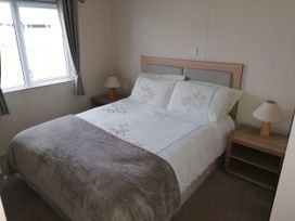 A bedroom with a bed and lamp at Seaside Lodge Retreat in Eyemouth