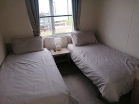 A bedroom with two beds and a bedside table at Seaside Lodge Retreat in Eyemouth