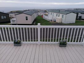 A deck with flowerpots overlooking caravans at Seaside Lodge Retreat in Eyemouth