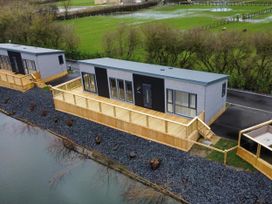 A lodge with a wooden deck by a water body at Malton 2Bed Lodge Sleeps 4 Pet Friendly in Malton