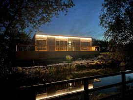 A lodge with lights and a deck reflecting in a pond at Malton 2Bed Lodge Sleeps 4 Pet Friendly, Malton