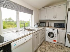 A kitchen with a sink, dishwasher, and washing machine at Biddy Granny's