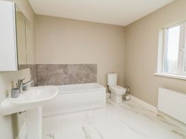 A bathroom with a bathtub, toilet, sink and window at Biddy Granny's 
