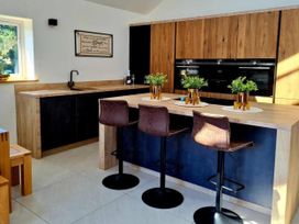 A kitchen with a sink and bar stools at 4 Bed Villa Sleeps 8 Private Terrace Free parking Near St Austell