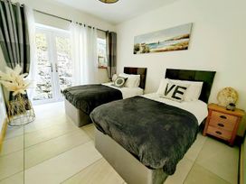 A bedroom with twin beds and a side table at 4 Bed Villa Sleeps 8 Private Terrace Free parking Near St Austell