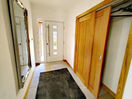 A hallway with a mirror and front door at 4 Bed Villa Sleeps 8 Private Terrace Free parking Near St Austell