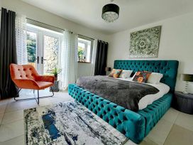 A bedroom with a bed and chair at 4 Bed Villa Sleeps 8 Private Terrace Free parking Near St Austell